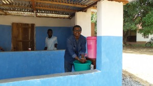 END in Africa Technical Advisor Dr. Joseph Koroma complies with mandatory handwashing before entering District health  compound in Bo, Sierra Leone. Photo: FHI360