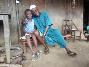 Wearing her new TOMS shoes, Fatmata gets a hug from her father, a volunteer who distributes medicines to prevent NTDs in Sierra Leone. Photo: Helen Keller International