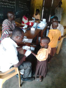 A health worker collects a blood sample from a brave young girl in Ghana to test for lymphatic filariasis. Photo: FHI 360