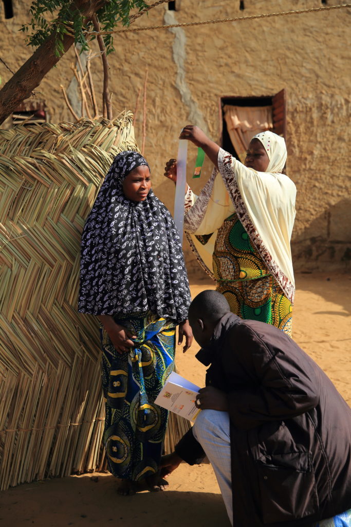 Health workers measure a girl in Burkina Faso to correctly dose NTD medicine. Photo: HKI